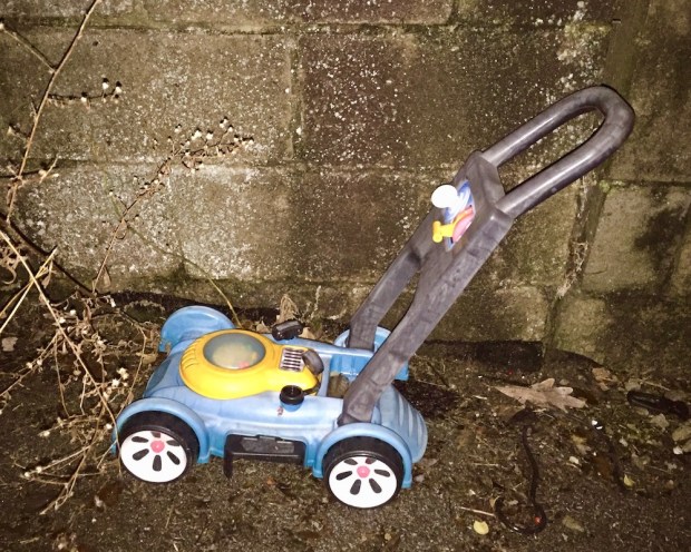 toy lawnmower left in alley