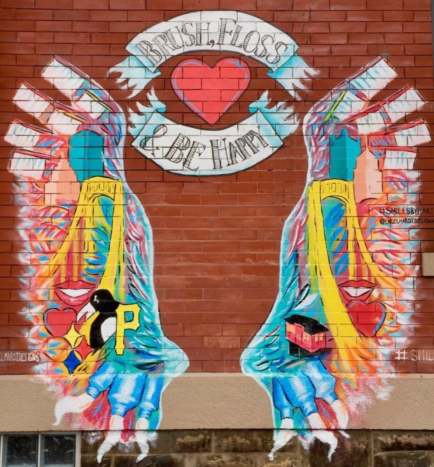 mural painted on brick wall for Smiles by Hart dentist office including Pittsburgh imagery, toothbrushes, toothpaste, and the banner message "Brush, Floss & Be Happy"