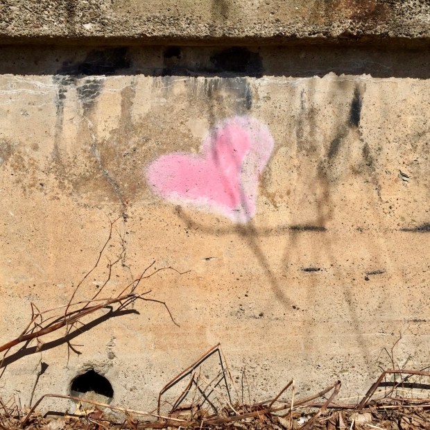 small pink heart painted on cement retaining wall