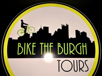 sign for Bike the Burgh Tours with a bicycle rider on a silhouette of the Pittsburgh skyline