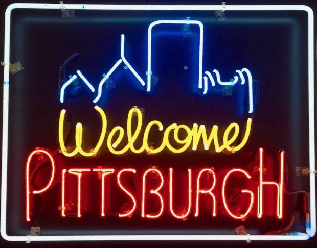 neon sign for Welcome Pittsburgh including part of the downtown skyline