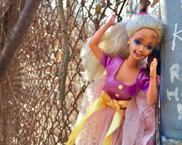 Barbie doll attached to chain link fence