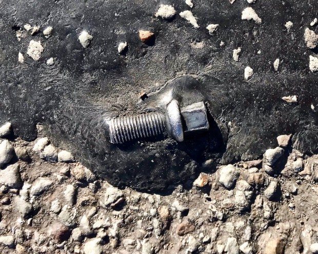 machine screw embedded in road tar