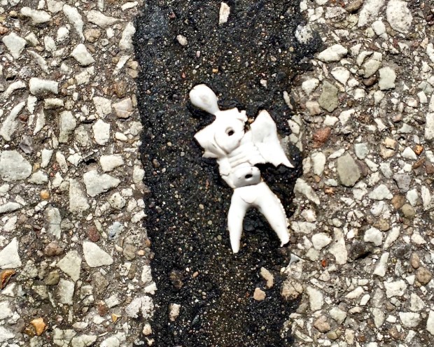 white plastic figure embedded in road tar