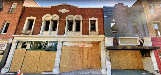 two brick retail buildings in downtown New Kensington, PA with second floor windows removed and plywood covering the storefronts