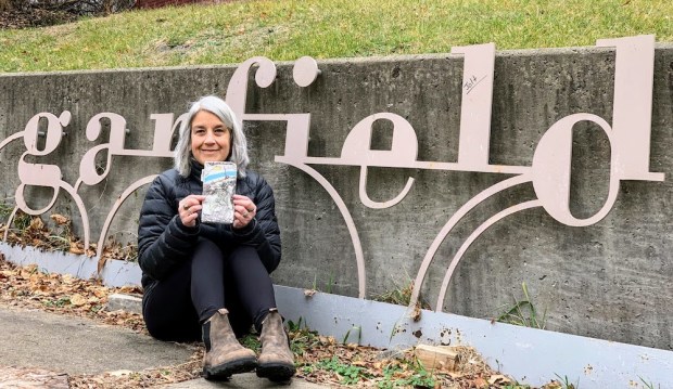 artist Lisa Valentino posing with a completed walking map of a section of Pittsburgh