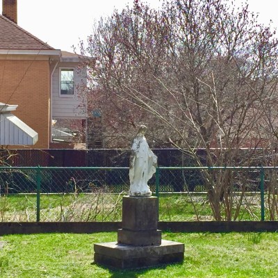 statue of Mary on pedestal in residential backyard