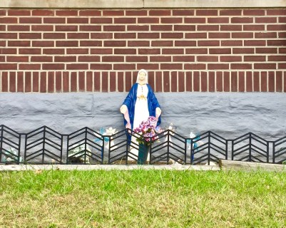 statue of Mary in front of brick house
