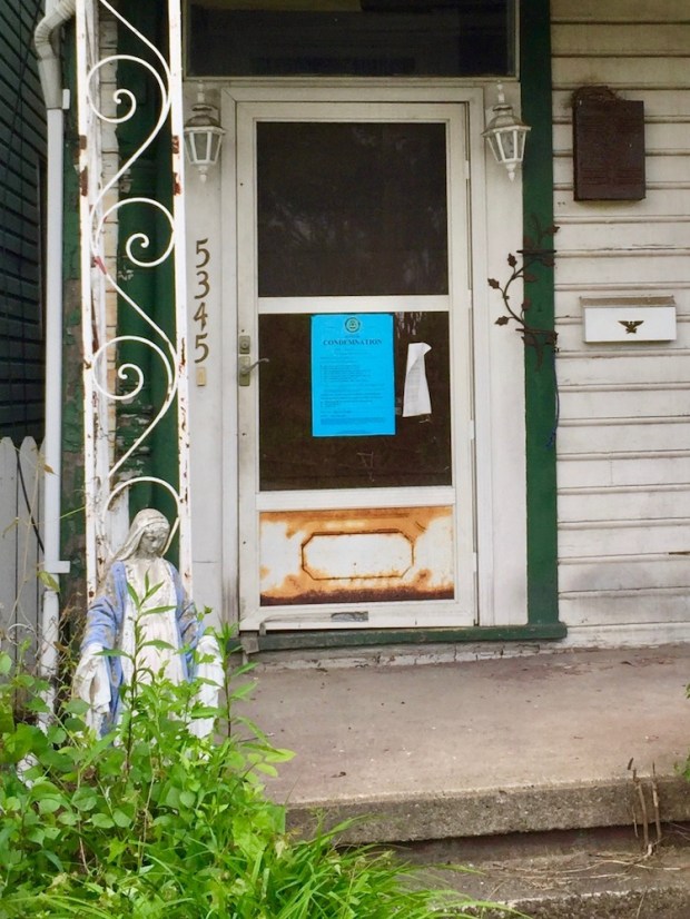 statue of Mary in front of house with condemned notice