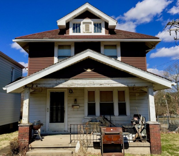 statue of Mary in front of wood frame house