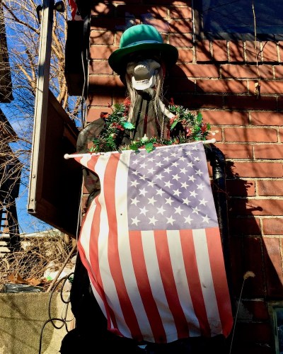 skeleton decorated with green hat, Christmas garland, and American flag