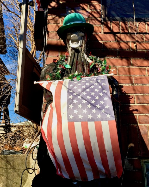 skeleton decorated with green hat, Christmas garland, and American flag