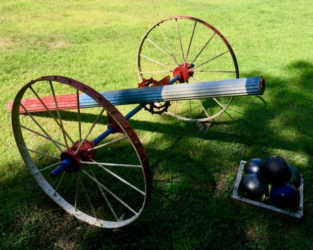 sculpture of cannon made from wagon parts and bowling balls