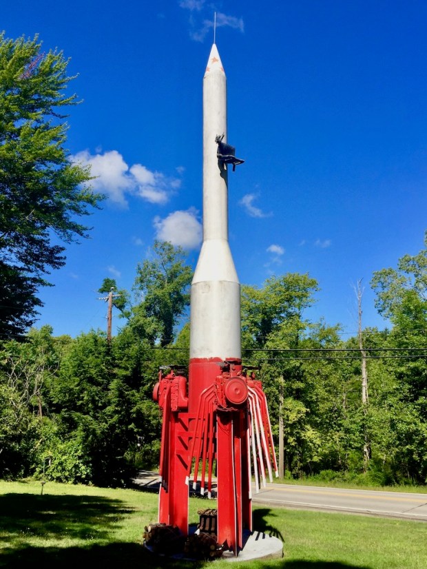large outdoor sculpture of a rocket made recycled parts