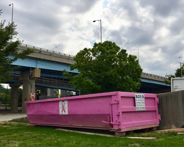 pink breast cancer awareness dumpster by highway overpass