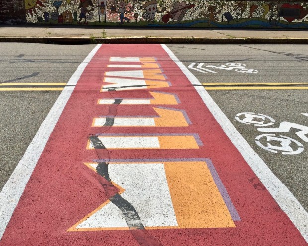 street crosswalk mural reading "Millvale"