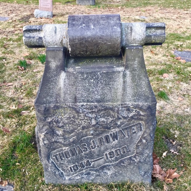 stone grave marker featuring large spinning machine part