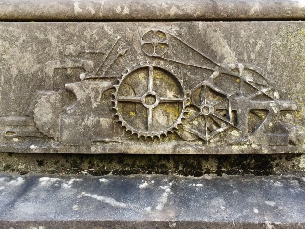 detail from cemetery monument featuring chiseled gears/machine imagery