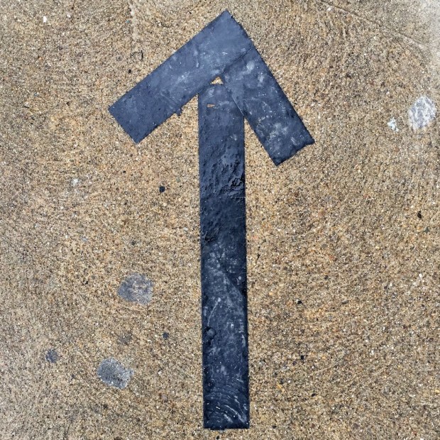 arrow made of black duct tape on cement sidewalk