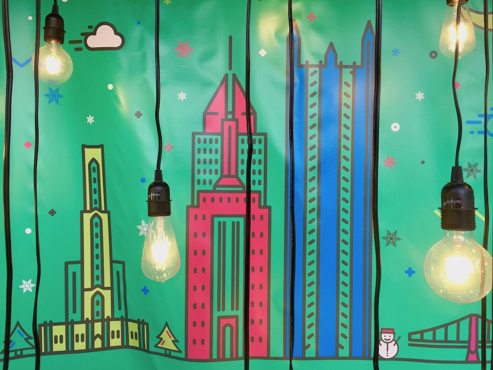 store window display of artist painted iconic buildings of Pittsburgh with light bulbs