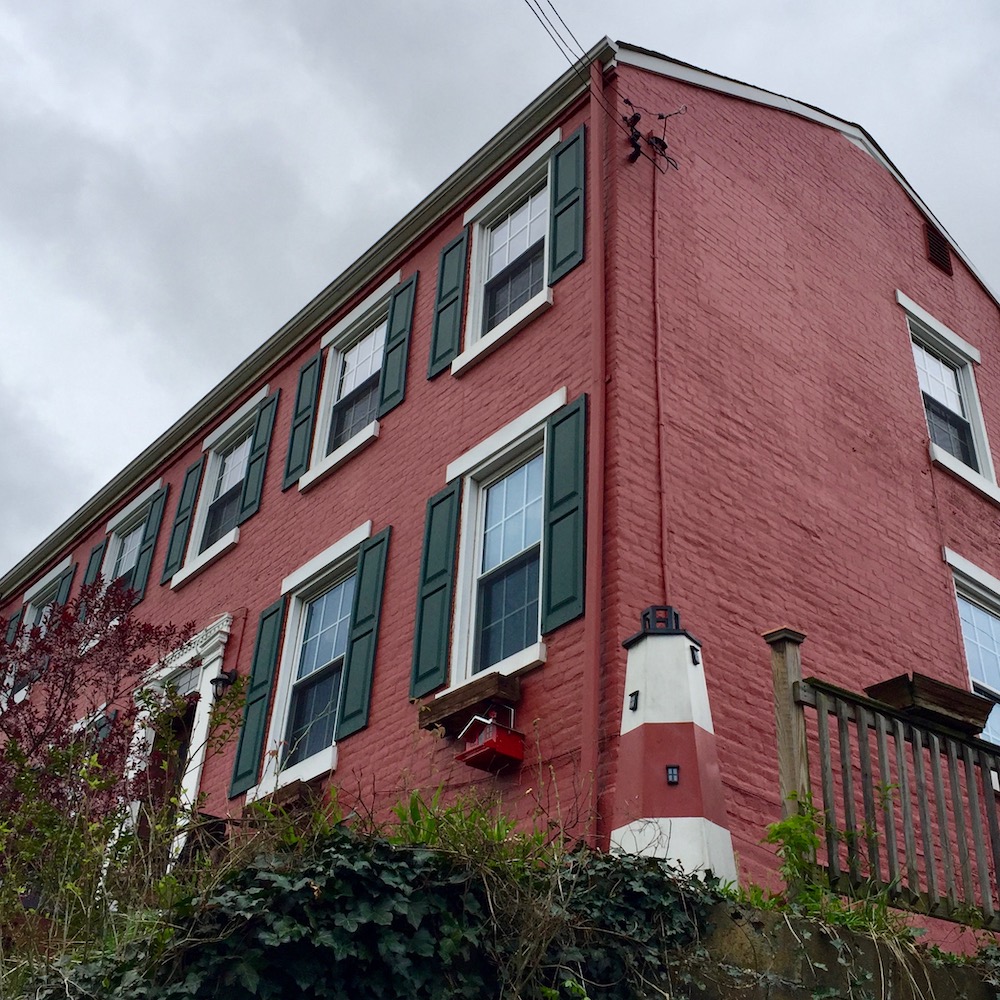 decorative red and white lighthouse lawn ornament in front of red brick house