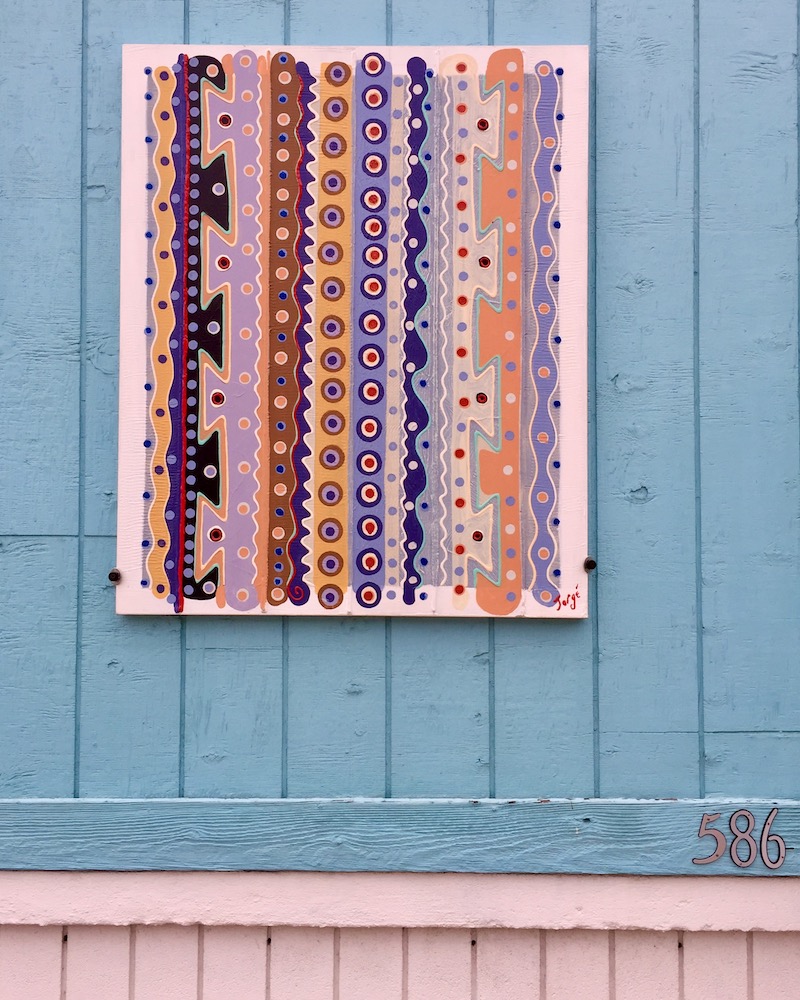 painting of patterns that look aboriginal hung on exterior of house