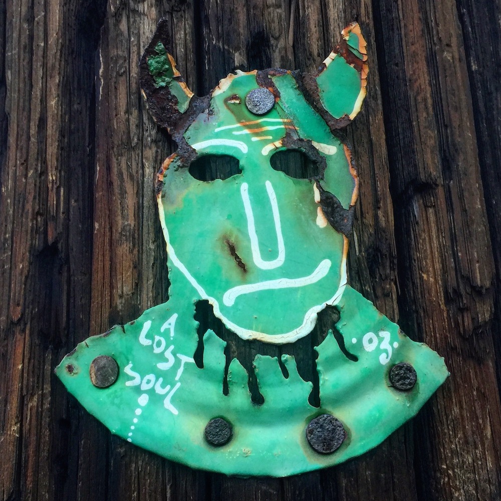 painting of devil made from cut steel can nailed to utility pole