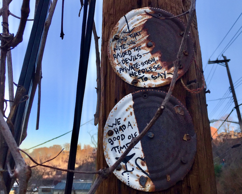 rusted paintings on tin can nailed to utility pole