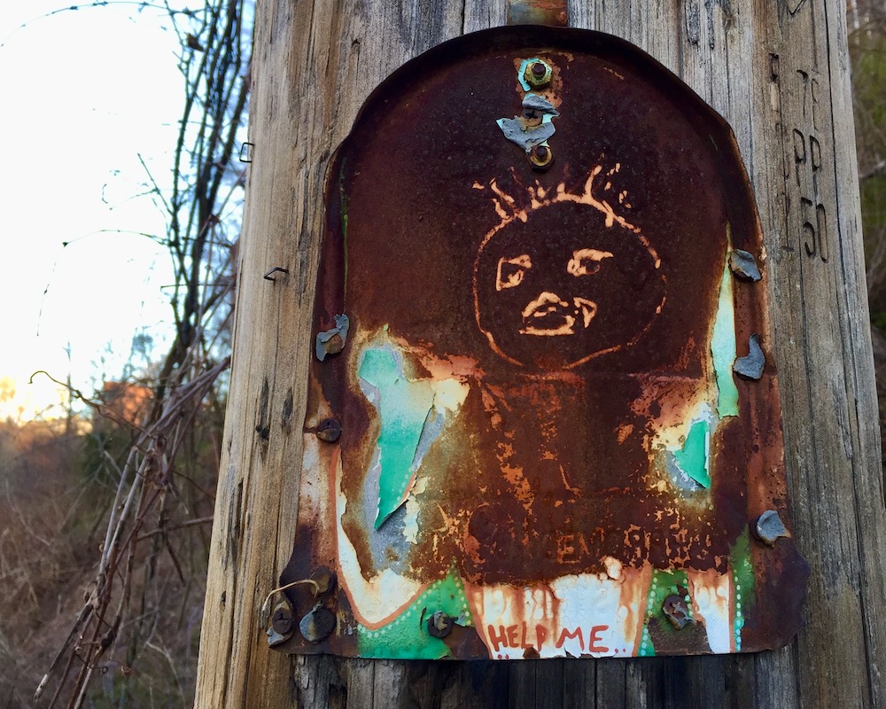 rusted painting on tin can nailed to utility pole