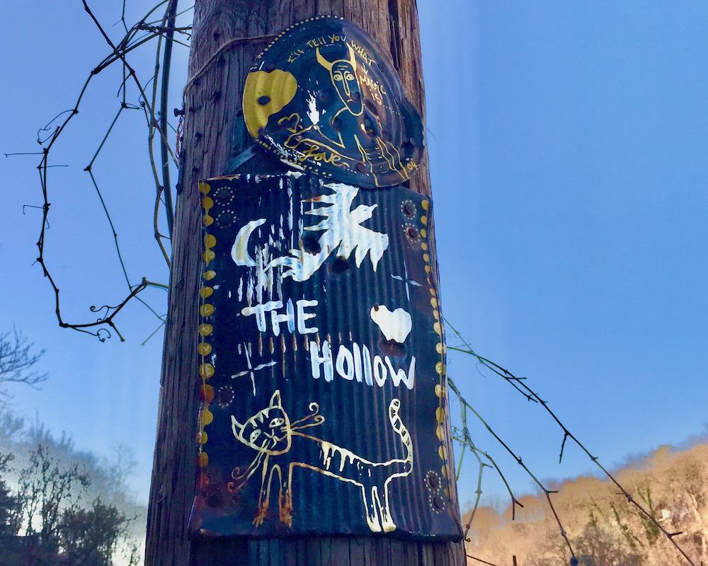 paintings made from flattened tin cans nailed to a utility pole