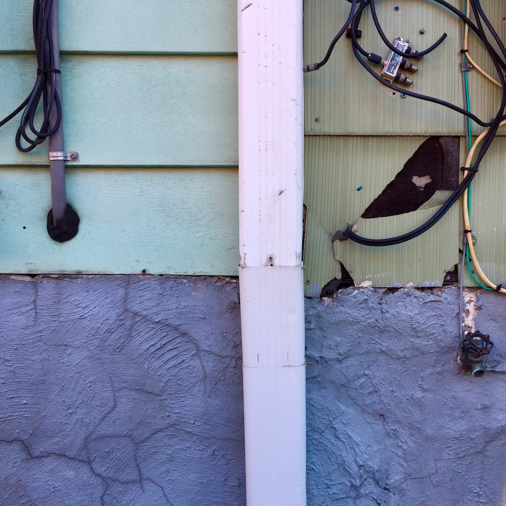 detail of painted row house walls and foundation showing distinct square quarters of different shapes and colors