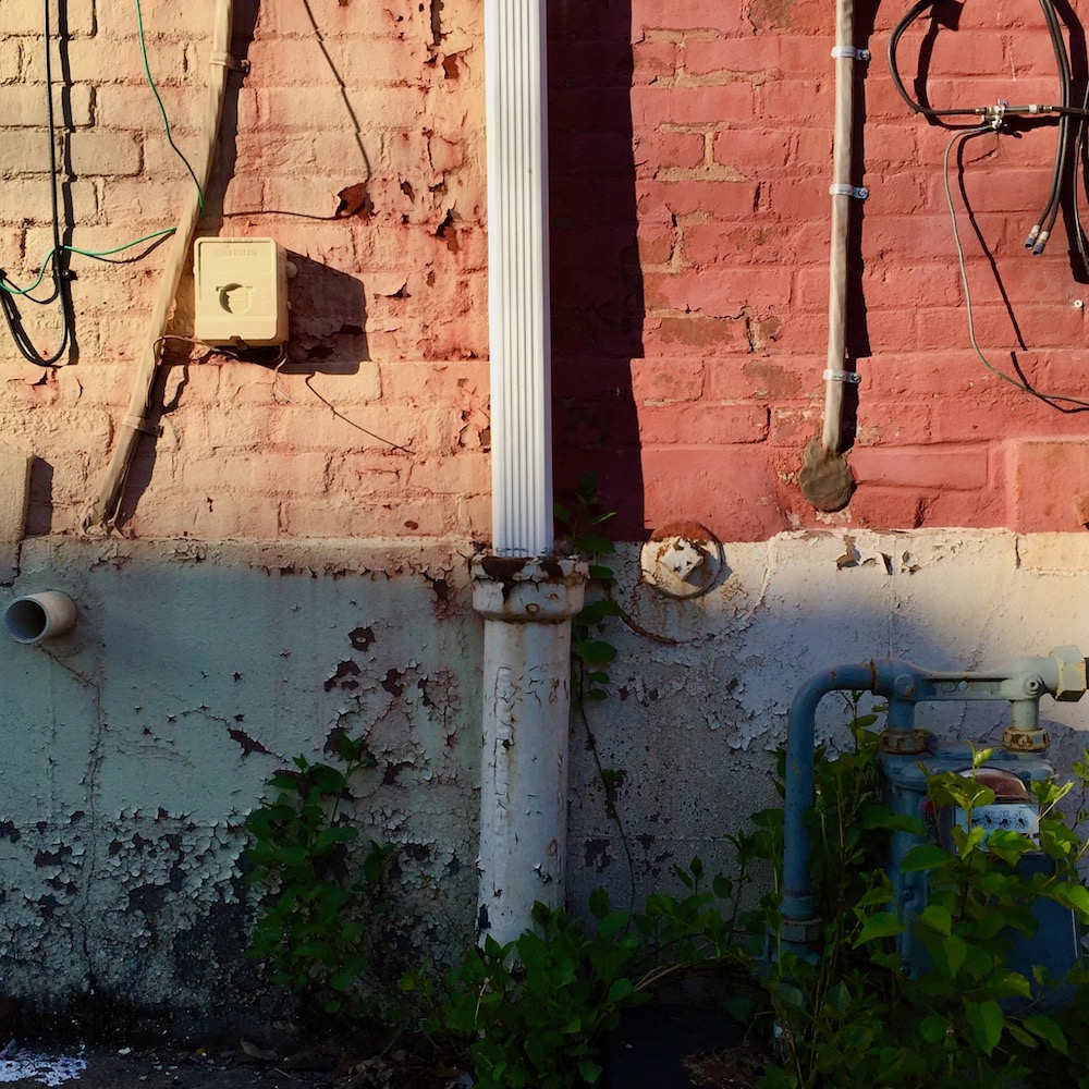 detail of painted row house walls and foundation showing distinct square quarters of different shapes and colors