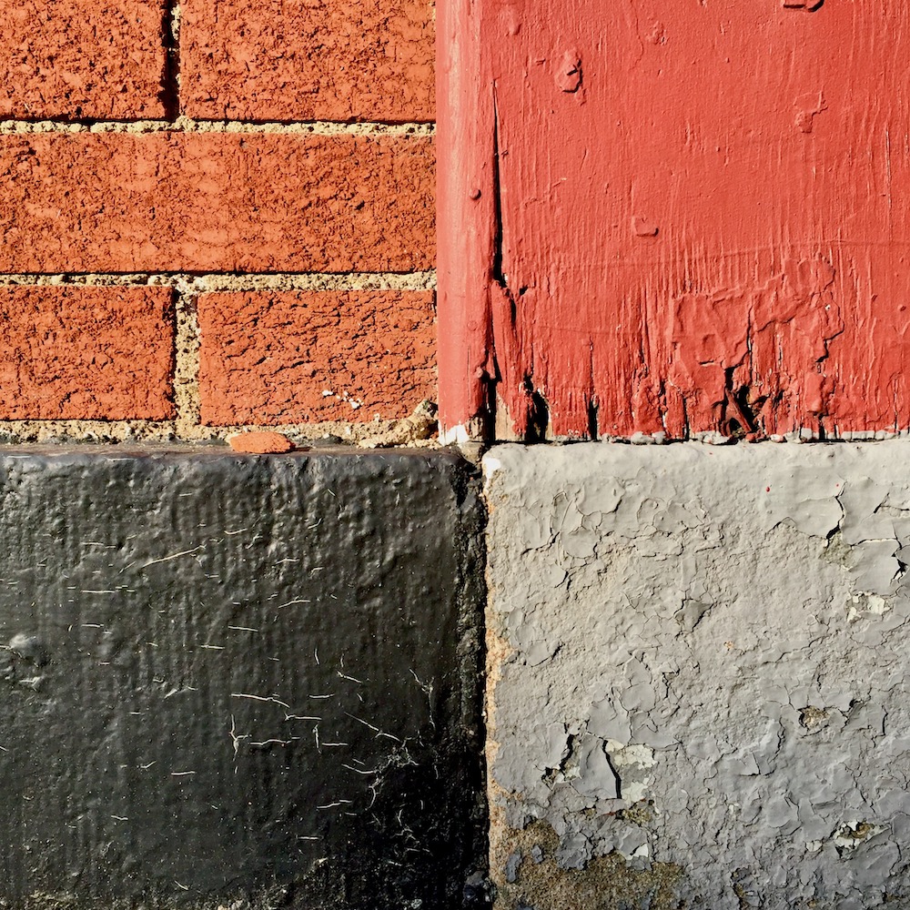 detail of painted row house walls and foundation showing distinct square quarters of different shapes and colors