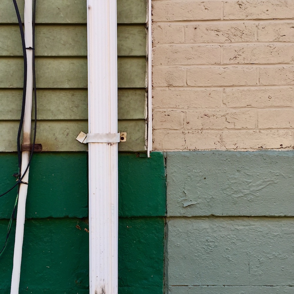 wall surface with geometric shapes formed by paint colors, siding, drain pipe