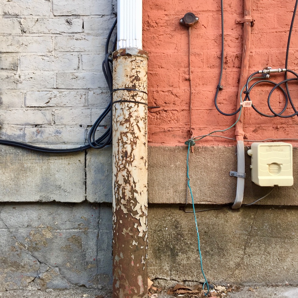detail of painted row house walls and foundation showing distinct square quarters of different shapes and colors