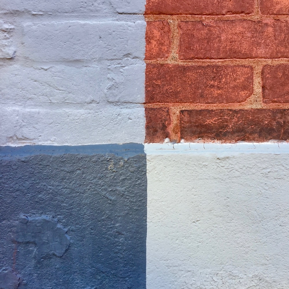 closeup of bricks meeting foundation of two rowhouses, forming equal square quandrants