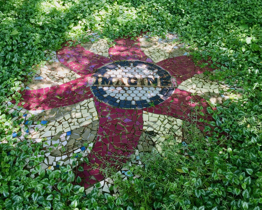 large ceramic piece reading "Imagine" surrounded by lush green groundcover