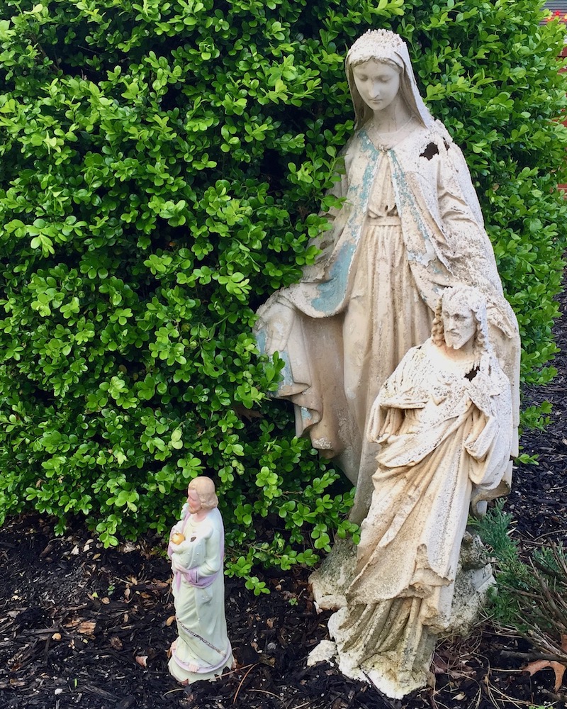 statues of Mary and Jesus by large bush