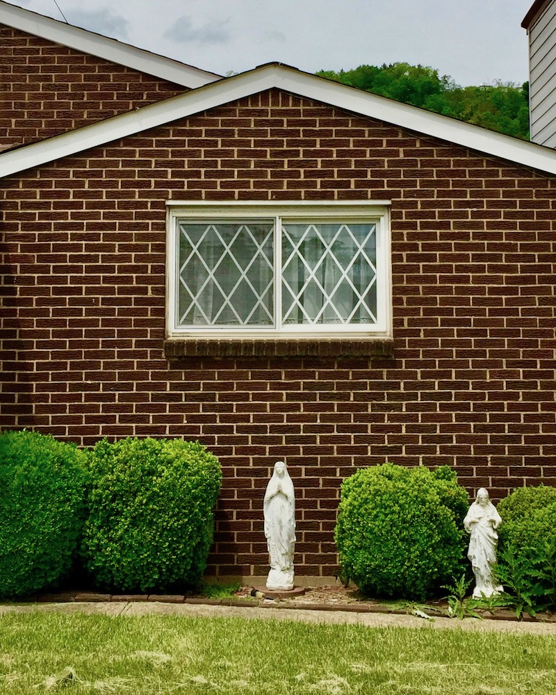 ceramic statue of Mary in front of brick house