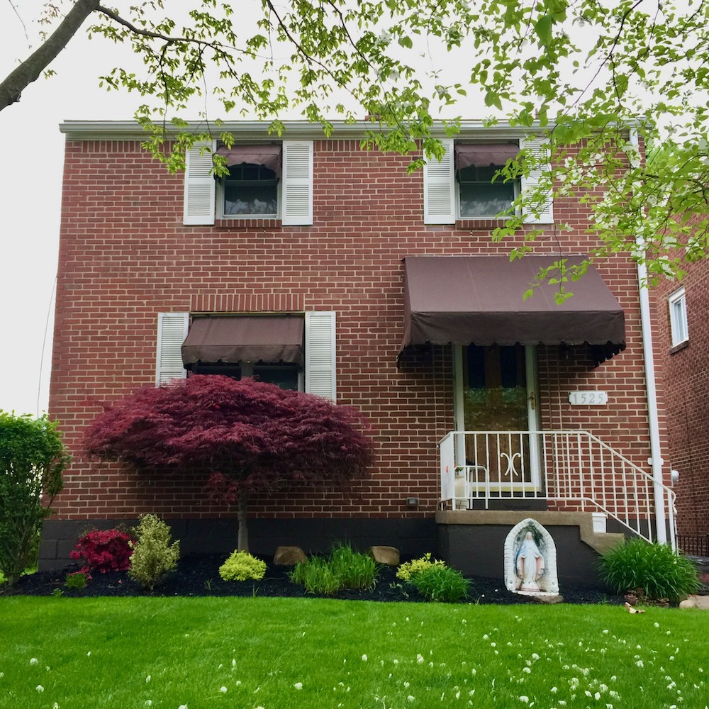statue of Mary in front of brick house with big yard