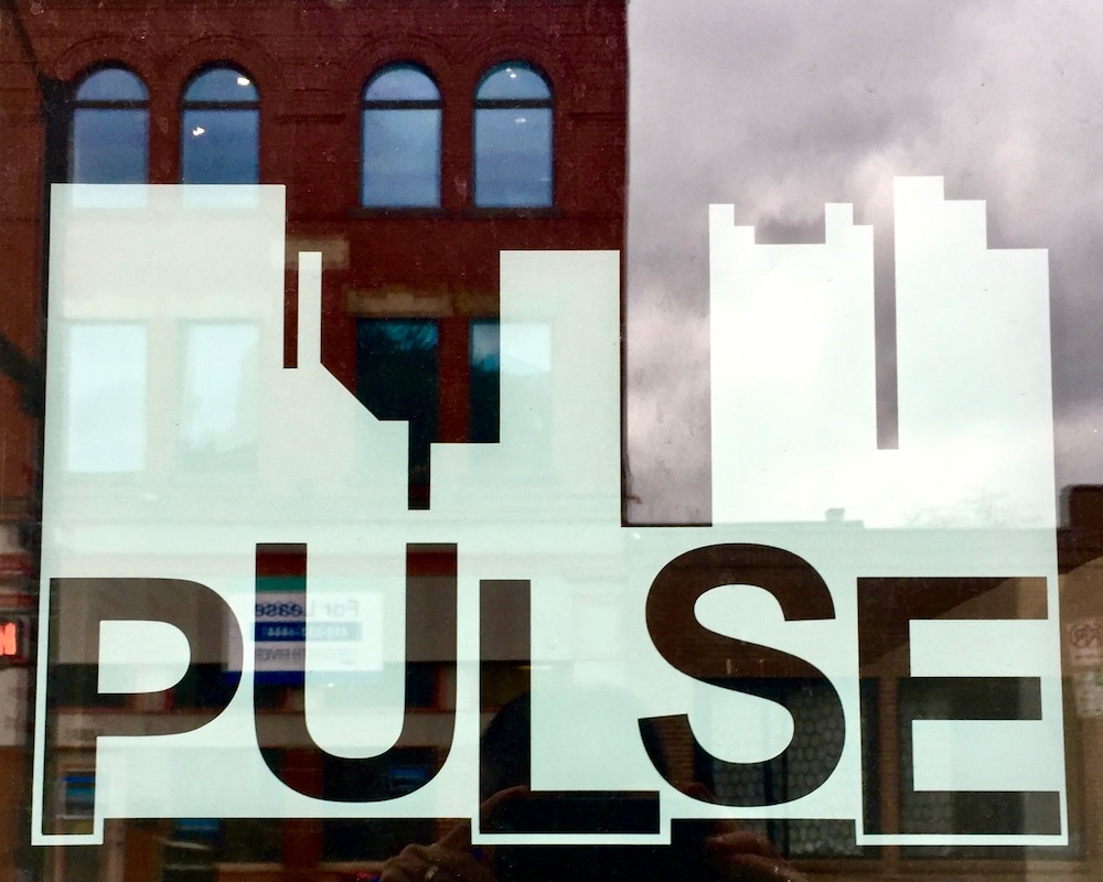 window sign for Pulse including abstracted downtown Pittsburgh skyline