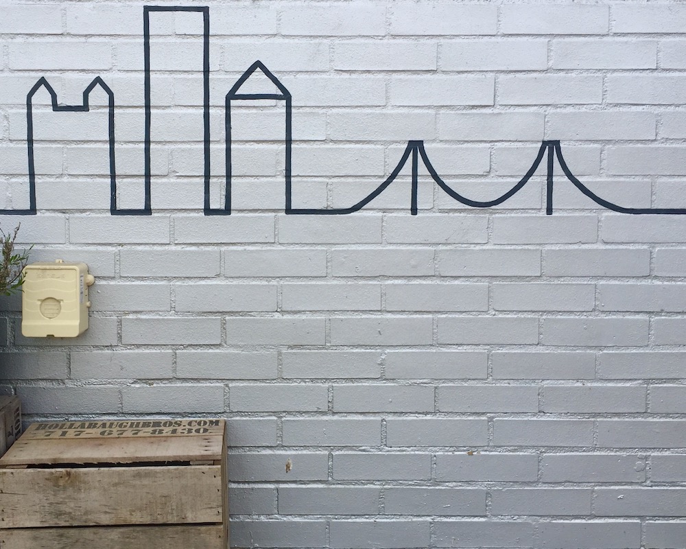 simple line painting on brick of downtown Pittsburgh buildings and bridge