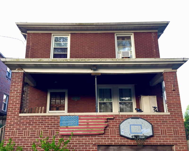 handmade American flag made from recycled wood attached to brick house