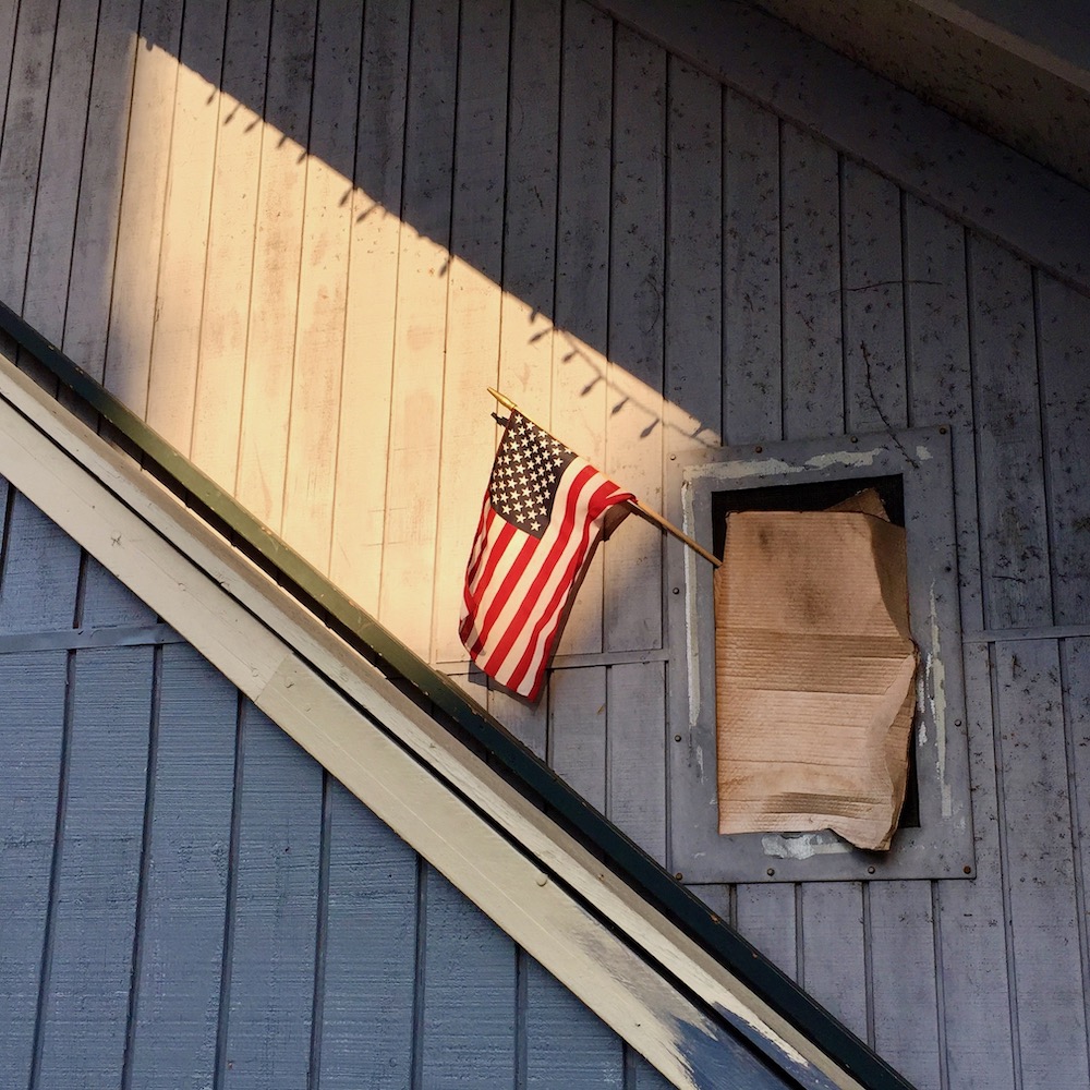 small window covered in cardboard with American flag sticking out