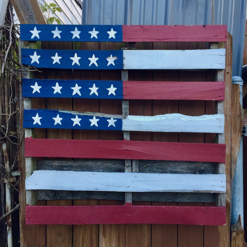 shipping pallet painted like the American flag, hung on alley fence