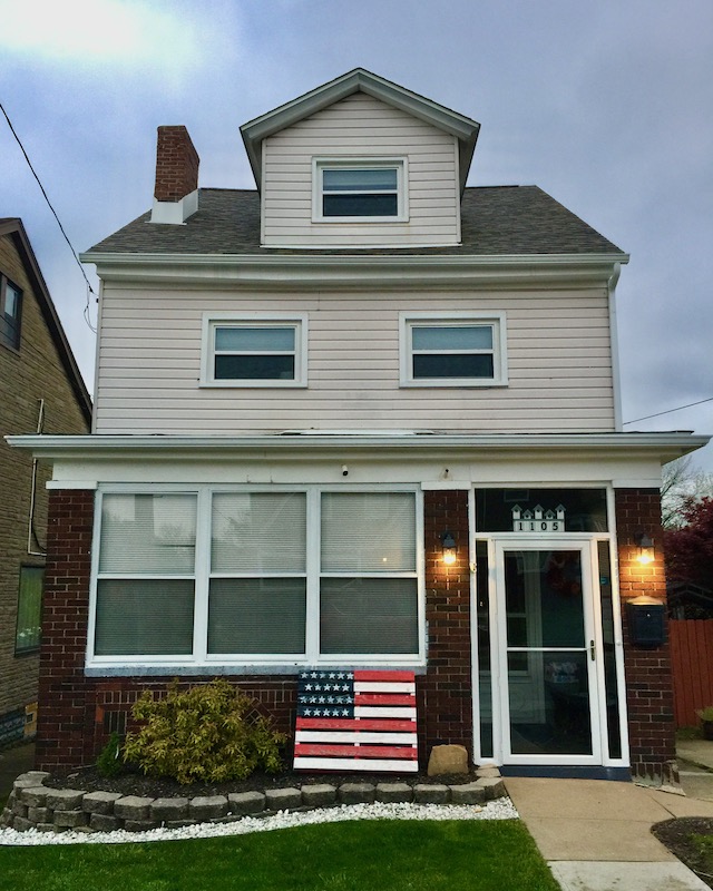 shipping pallet painted like the American flag in front of brick house