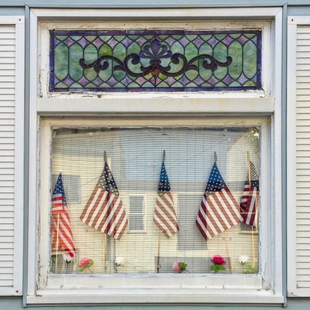 row house window decorated with multiple American flags