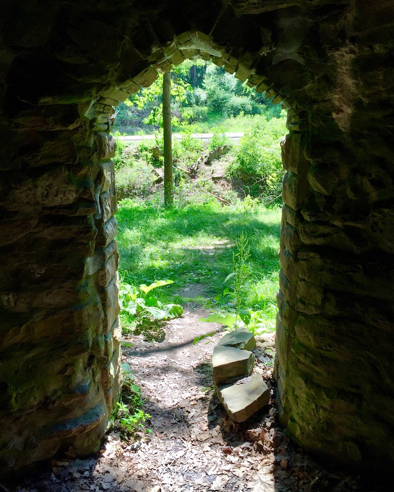view through stone doorway to sunny wooded area