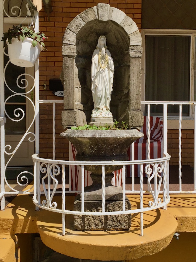 statue of Mary in grotto enclosure on pedestal in special attachment to front porch