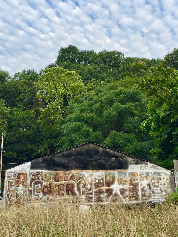 large metal shed painted with elaborate abstract designs and text "Coker"